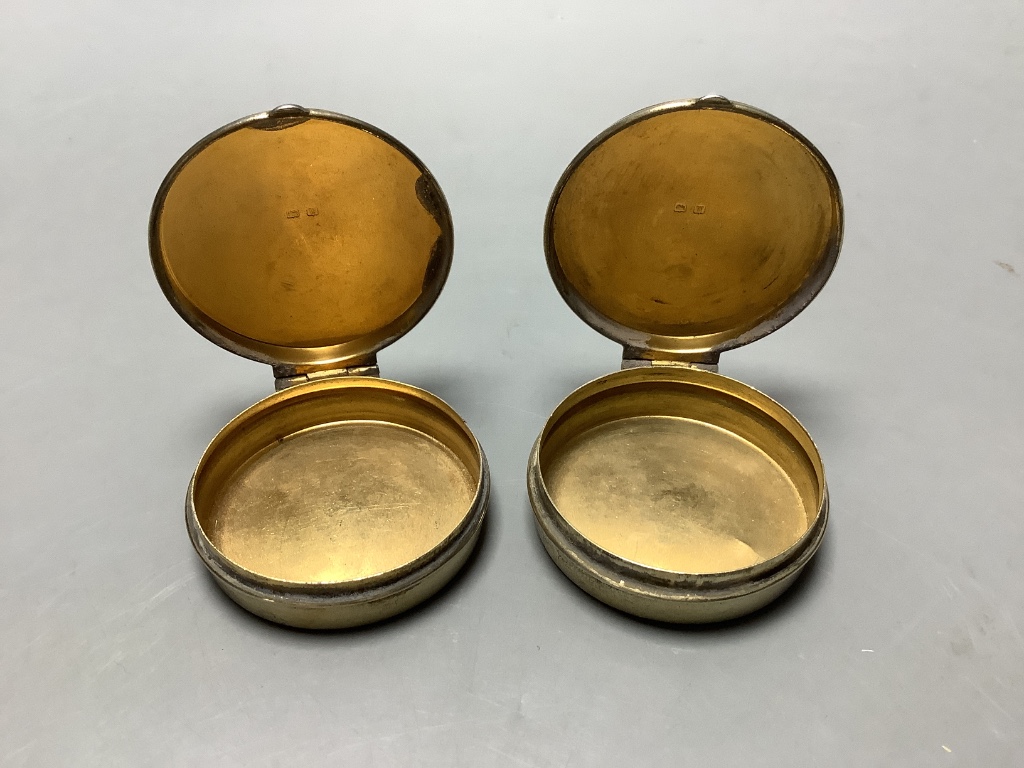 A pair of George V circular silver gilt pill boxes by Asprey Ltd, Birmingham, 1921, 47 mm, together with a silver mounted glass cayenne pepper jar with figural lid.